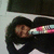 Pixelated image of a person with dark hair wearing a dark top, holding a colorful object against a light background.