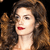 Pixelated close-up of a person with long brown hair, red lips, and light skin against a dark background.