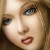 Pixelated close-up of a person's face with light brown hair, showing eyes, nose, mouth, and skin tones in warm beige and pink hues.