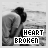 Black-and-white image of two figures embracing by water with 'HEART BROKEN' text, where the letter A in HEART changes color across frames.