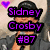 Pixelated image of a person wearing a black cap and gray jacket holding a microphone, with purple text overlays and a purple heart symbol.