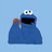 Blue pixelated character with large white eyes and black pupils, open mouth showing dark interior, holding orange object against light blue background.
