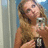 Pixelated image of a person with long light brown hair holding a microphone, standing near a window with a light blue background and the word 'taylor' in black text.