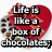 Red heart-shaped box of chocolates with visible chocolate pieces, overlaid with black text reading "Life is like a box of chocolates; you never know what you're gonna get. - Forest Gump".
