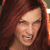 A pixelated close-up of a person with long reddish-brown hair, showing a mouth with teeth and a partially open mouth expression.