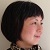 Pixelated profile view of a person with short dark hair against a light background, wearing a dark patterned top.