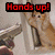 A pixelated cat with light brown fur sits against a blurred background, raising its paws while red text reads 'Hands up!' above it.