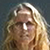 Pixelated close-up of a person with long light brown hair against a dark background, showing partial facial features and hair texture.