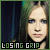 Pixelated image of a person with light brown hair and blue eyes, wearing dark clothing against a dark background with vertical greenish streaks.