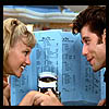 Two people face each other in a close-up, one holding a small camera-like device with a blue background featuring text.