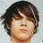 Static pixelated image of a person with dark brown hair, light skin tone, and closed eyes against a pale gray background.