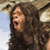 Pixelated image of a person with long dark hair, mouth open in a shout, against a blurred background with light and dark tones.