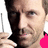 Pixelated close-up of a person holding a black object near their face with one hand, wearing a bright pink garment on the right side.