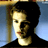 Pixelated static image of a person with dark hair and light skin against a blue background, wearing a black top.