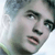 Pixelated close-up of a person's face with light skin tone, dark eyebrows, and dark hair, showing partial facial features against a light background.