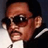 Pixelated close-up of a person wearing dark sunglasses, a white shirt, and dark jacket, with a blurred background.
