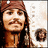 Pixelated static image of a person with long dark hair, brown head covering, and light skin tone against white background.
