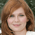 A static pixelated image of a person with light brown hair, fair skin, and a neutral expression, set against a blurred green background.