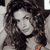 Pixelated grayscale image of a person with long dark hair, wearing a dark top, and holding an orange object near the lower right.