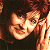 Pixelated close-up of a person with light skin tone, dark hair, and warm-toned lighting against a dark background.