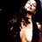 Pixelated static image of a person with light skin and dark hair wearing a white sleeveless dress against a black background, showing partial upper body and hand gestures.