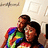 Two figures embrace; one wears a rainbow-colored garment with visible red, blue, green, yellow pixels.