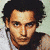 A pixelated image of a person with dark curly hair, light skin tone, and visible facial features including eyes, nose, mouth, and forehead wrinkles.