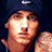 Static pixelated image of a person's face with visible facial features and partial shoulder, set against dark background.