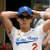A person wearing a blue cap and white shirt with blue text and red number 2, holding arms behind head in a pixelated static image.