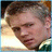 Pixelated close-up of a person's face with brown hair, light skin tone, and visible facial features including eyes, nose, mouth, and ear.