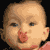 Pixelated close-up of a baby's face with light skin, brown hair, and red cheeks against black background.