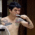 A shirtless person with short dark hair and visible tattoos brushes teeth in a bathroom setting across four