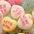 Heart-shaped candy pieces with red text on pastel-colored backgrounds, arranged in a