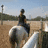 A pixelated image shows a person riding a white horse in an outdoor setting with a clear sky and distant structures.