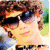 Four- shows a person with curly brown hair in various poses: sunglasses outdoors, close-up white background, three figures on pink, and side profile dark clothing