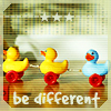 Three rubber duck toys on red wheels, two yellow and one blue, arranged in a row with 'be different' text below and three white stars above on a checkered background.