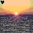 Pixelated sunset scene with gradient sky transitioning from peach to yellow, a bright sun at the horizon over water reflecting purple and blue hues.