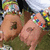 A person's arm and hand wearing a colorful beaded bracelet, with the hand moving from a relaxed position to a pointing gesture against a grassy background.