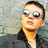 Pixelated close-up of a person wearing dark sunglasses and a black jacket against a blurred background.
