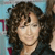Pixelated close-up of a person with curly dark hair, light skin, and closed eyes against a blue background with red accents.