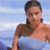 A pixelated image shows a person with short dark hair wearing a sleeveless top, standing against a light blue background with horizontal stripes.