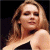 A pixelated image of a person with long light brown hair wearing a dark one-shoulder garment against a black background, next to green text reading 'Original Icons .com'.
