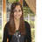 A pixelated portrait of a person with long brown hair wearing dark clothing against a blurred background.
