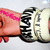 A pixelated image shows a hand holding a white and black sneaker with visible laces against a light background.