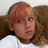 A pixelated image of a person with light brown hair in pigtails wearing a white shirt, next to pink text on black background.