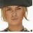 Pixelated static image of a person with light brown hair wearing a dark cap, visible from the shoulders up against a white background.
