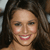 A static pixelated image of a person with long dark hair, light skin, and a smiling expression showing teeth.