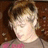 Pixelated static image of a person with light skin tone, brown hair, and a pink garment against a dark brown background.