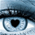 A pixelated eye with a black heart-shaped pupil, dark eyelashes, and light blue iris against a blurred background.