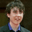 A pixelated image of a person with short brown hair wearing a dark jacket over a blue shirt, with cyan text reading "Neville's The Man" on a black background.